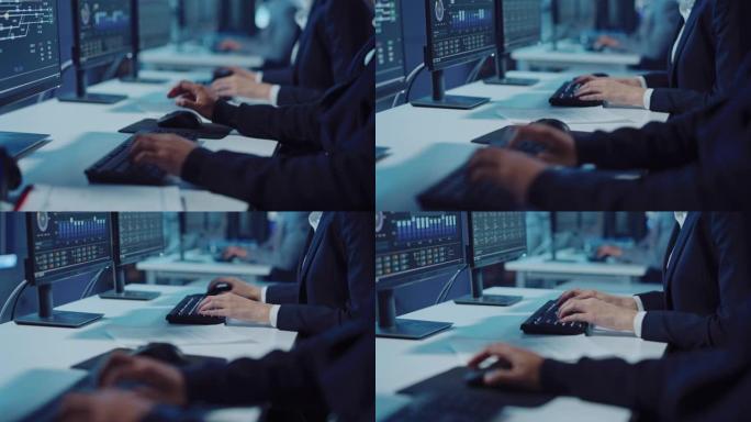 在黑暗的监视和控制室中，在计算机上工作的软件工程师的技术支持专家的特写镜头。他在键盘上打字并移动鼠标