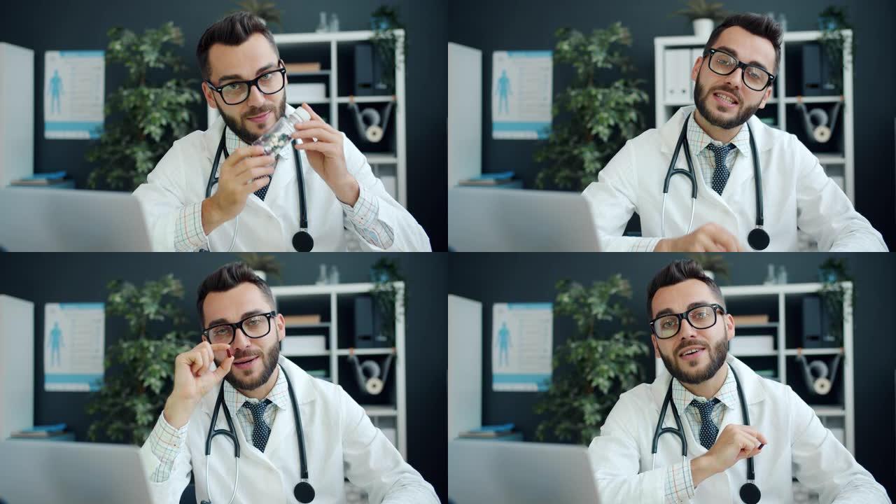 友好的年轻人的肖像医生在诊所里展示药片并看着相机说话
