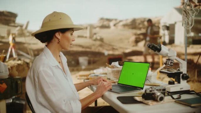考古挖掘地点: 女性考古学家使用绿屏色键显示笔记本电脑，分析化石遗迹，古代文明文化文物。历史学家在挖