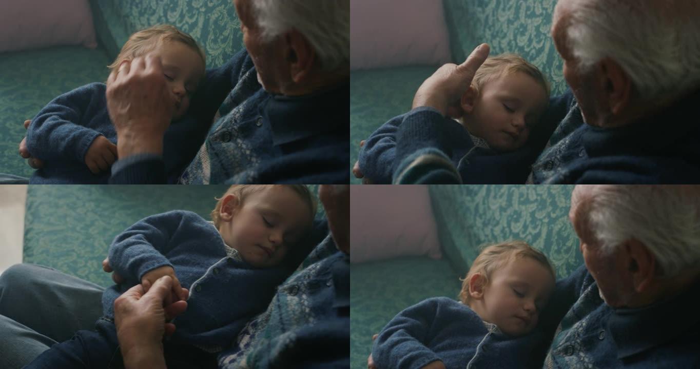 电影特写镜头高级白发祖父正在亲吻孙子婴儿，坐在家里的沙发上，安静地睡在手臂上。概念: 生活，祖父母，