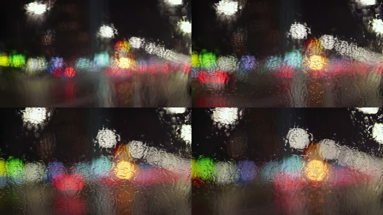 夜间城市交通穿过潮湿的车窗。镜头的平滑散焦。大城市概念中的秋天晚上。UHD, 4K