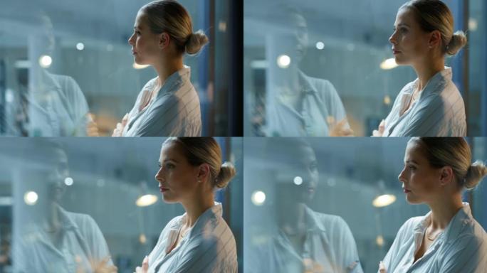一位年轻的女商人晚上在办公室透过玻璃窗看时思考。雄心勃勃的领导者和企业家感到鼓舞、激励和有能力在机会