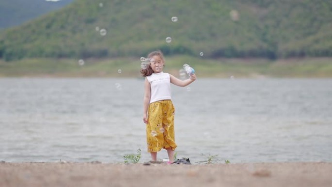 在湖边玩肥皂泡的快乐小女孩