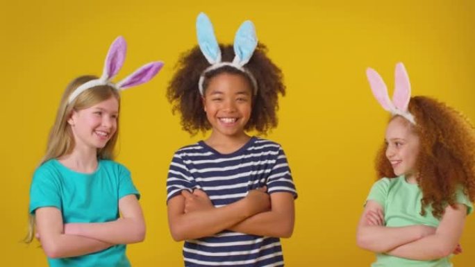 三个孩子在紫色背景下戴着兔子耳朵的工作室镜头-慢动作拍摄