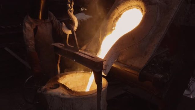 工厂工人在铸钢铸造厂的熔炼炉中倒入熔融金属的特写镜头