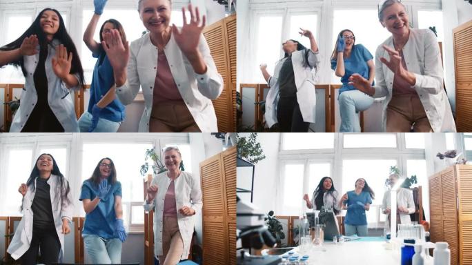 战斗冠状病毒结束。缩小三个有趣的多民族快乐的女医生在诊所实验室办公室一起跳舞。