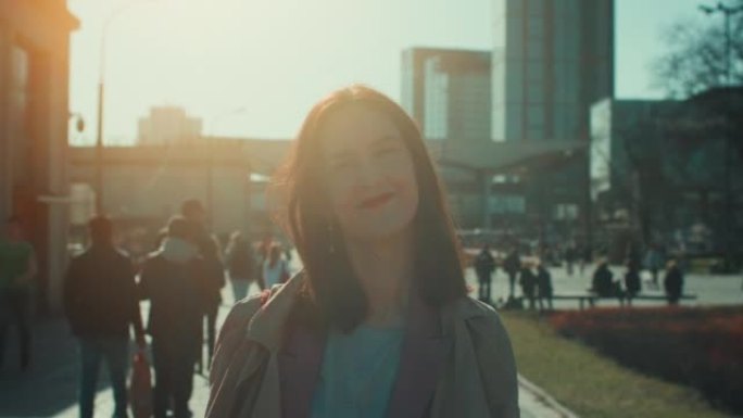 背光肖像美丽快乐安详的30岁高加索商人微笑在相机在秋天城市慢动作。