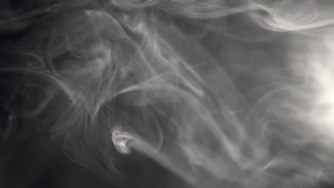烟雾背景。白烟的慢动作镜头漂浮在黑色背景上的空中。雾，火烟，蒸气在黑暗中缓慢移动