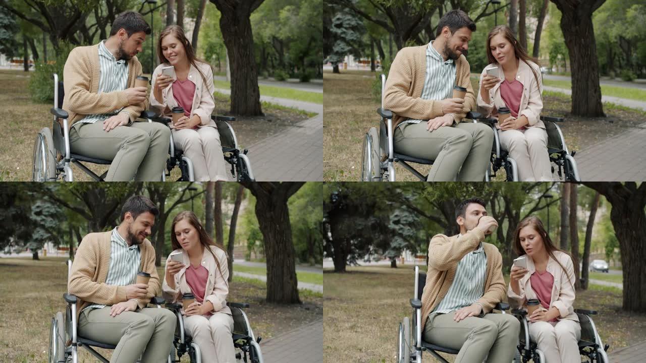 残疾夫妻坐在轮椅上聊天，使用智能手机在公园喝外卖咖啡