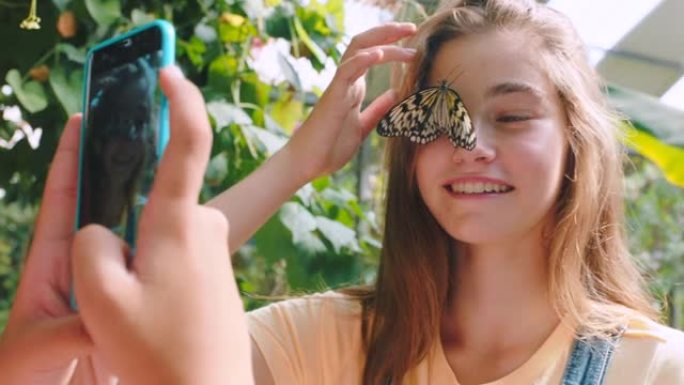 夏天，在大自然或动物园的社交媒体上，手机、摄影或脸上带着蝴蝶的女孩。快乐的孩子，内容创作或兴奋的青少