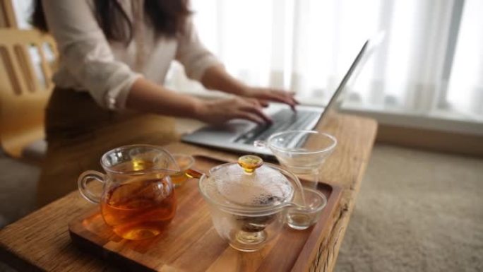 用茶杯在笔记本电脑上工作的女性特写