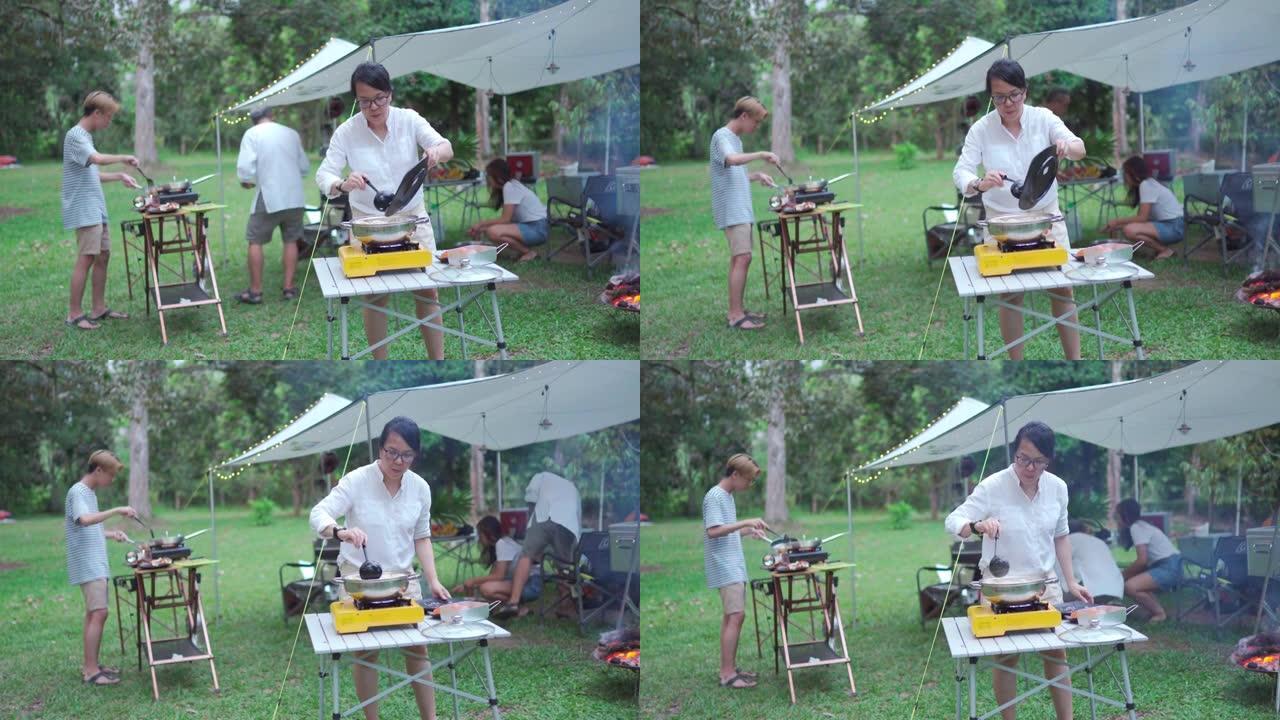 亚洲中国家庭有两个十几岁的后代在野营帐篷做饭准备晚餐