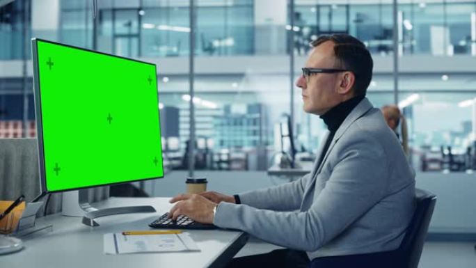 多元化的公司办公室: 时尚帅气的大数据工程师使用带有绿色色度键屏幕的台式计算机。从事电子商务项目营销