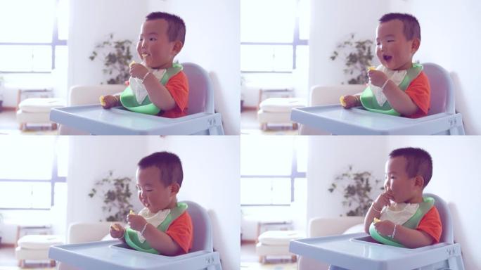 男婴坐在高脚椅上吃食物