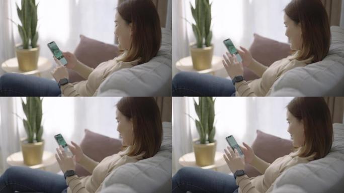 年轻的亚洲女性在家中放松身心时使用智能手机进行在线购物
