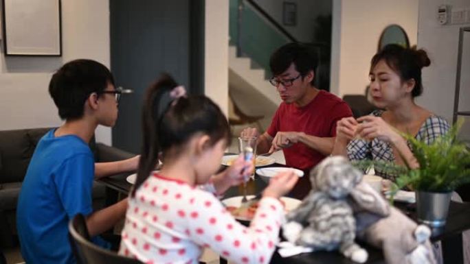 有两个孩子的亚洲中国年轻家庭周末早上在厨房一起吃早餐