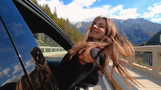 快乐的年轻女子玩得开心，在秋天的公路旅行中从车窗里倾斜