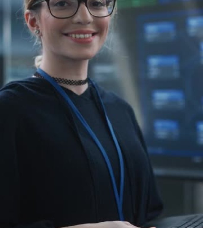 垂直屏幕: 一位戴着眼镜，使用笔记本电脑，看着相机并微笑的美丽女性的肖像。信息技术专家、软件工程师或