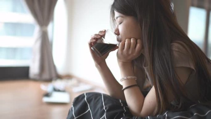 早上在卧室里躺着喝黑咖啡的亚洲中国美丽的长发女人