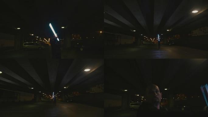 SLO MO Man晚上在城市的停车场上挥舞着霓虹灯