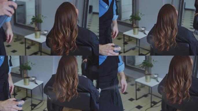 慢动作发型师在沙龙用女性顾客的喷雾来定型头发
