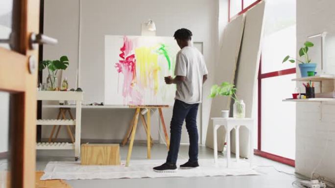 非裔美国男性艺术家在艺术工作室画布上绘画的后视图