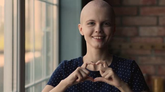 年轻秃头癌症患者妇女显示手指心形