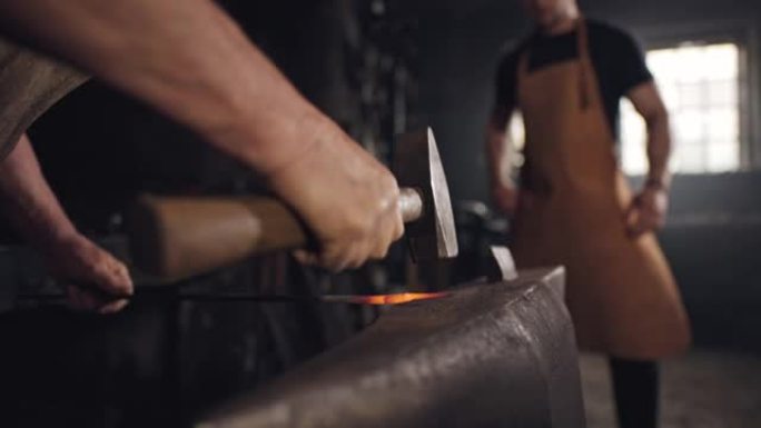SLO MO两个铁匠在铁砧上模制金属片