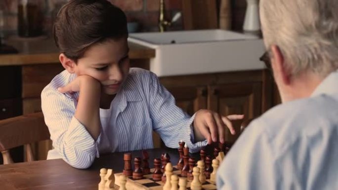 专注的小男孩和老爷爷下棋。