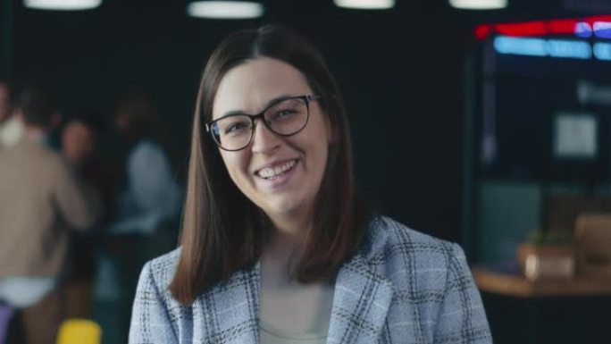 美丽快乐的30多岁女性领导，戴眼镜的公司老板，办公室背景下对着镜头微笑的正式服装。