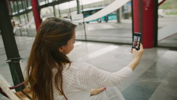 女人坐在购物中心时在智能手机上拍照