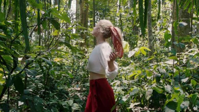 美丽的幸福女人在森林里跳舞，享受自然舞蹈，在郁郁葱葱的热带雨林里旋转