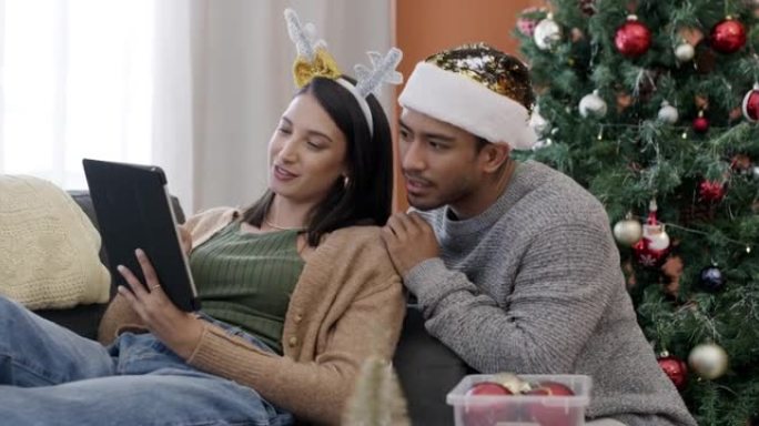 一对年轻夫妇在家中一起在沙发上使用数字平板电脑进行圣诞节最后一刻购物的4k视频片段