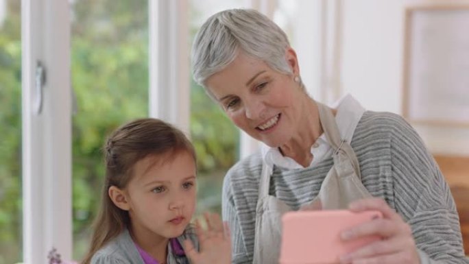 祖母和孩子使用智能手机进行视频聊天小女孩与奶奶分享假期周末，享受在家与孙女在手机上聊天