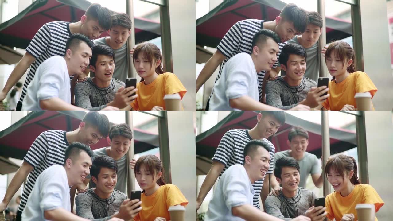 年轻的亚洲男人和女人一起在户外看手机