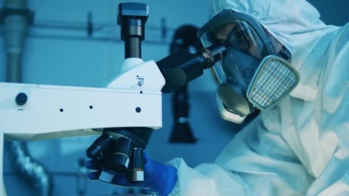 一个穿着危险品套装的男人正在使用显微镜进行分析