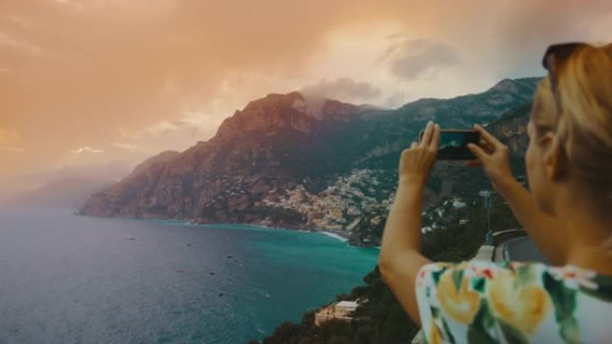 SLO MO女游客在日落时使用手机拍摄阿马尔菲海岸