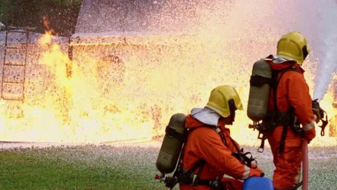 4k UHD消防员使用化学泡沫灭火器与油罐车事故产生的火焰进行战斗。消防员安全灾害事故与公共服务理念