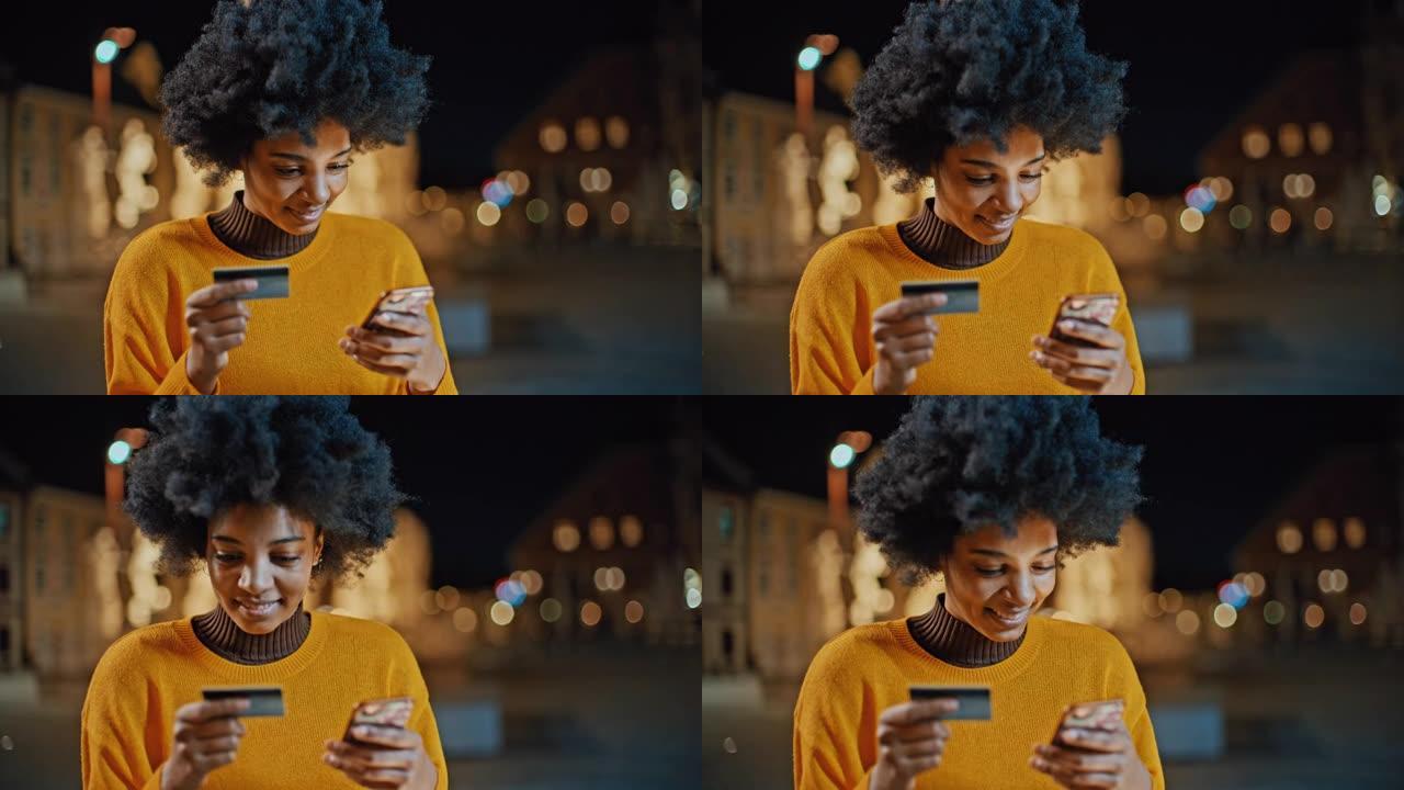 年轻的黑人妇女使用她的信用卡和智能手机进行在线支付