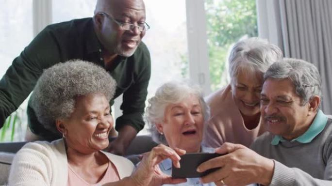 一群不同的老年人在家里一起使用智能手机