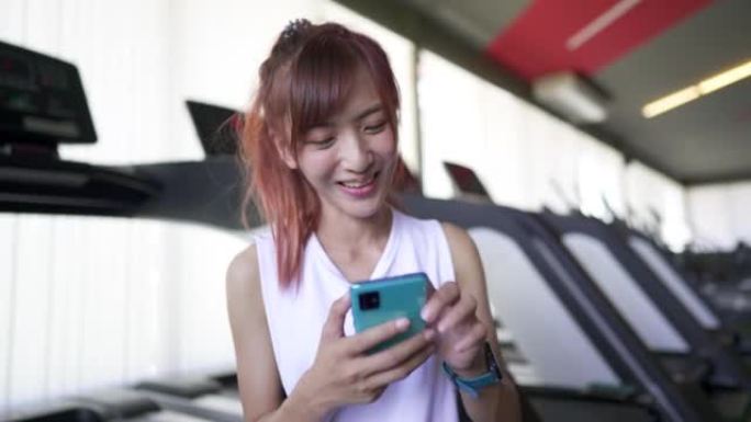 亚洲妇女在健身房使用电话进行视频通话