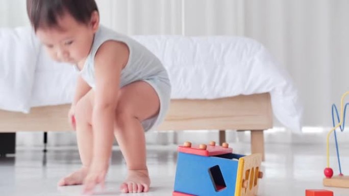 亚洲男婴年龄9个月玩彩色木制玩具积木呆在家里。东南亚和东亚: 亚洲婴儿