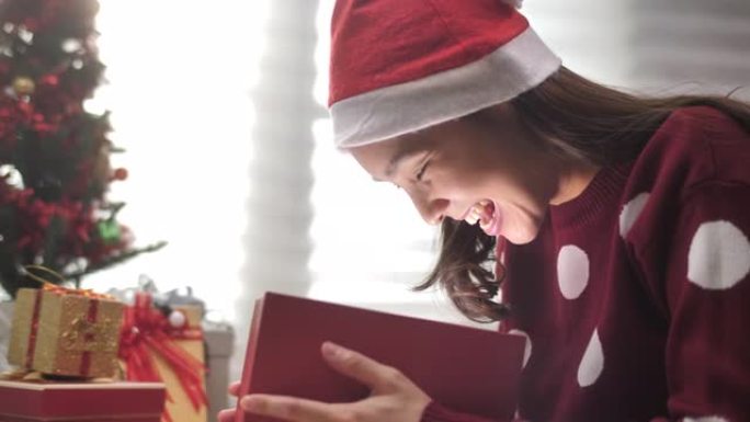 戴圣诞老人帽子的亚洲女人打开礼品盒圣诞节
