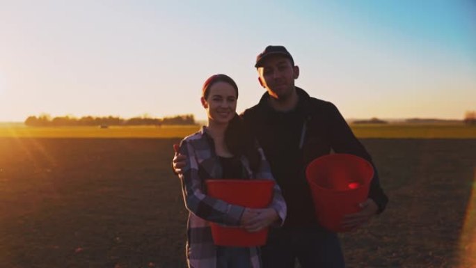 SLO MO农民夫妇拿着水桶对着镜头微笑