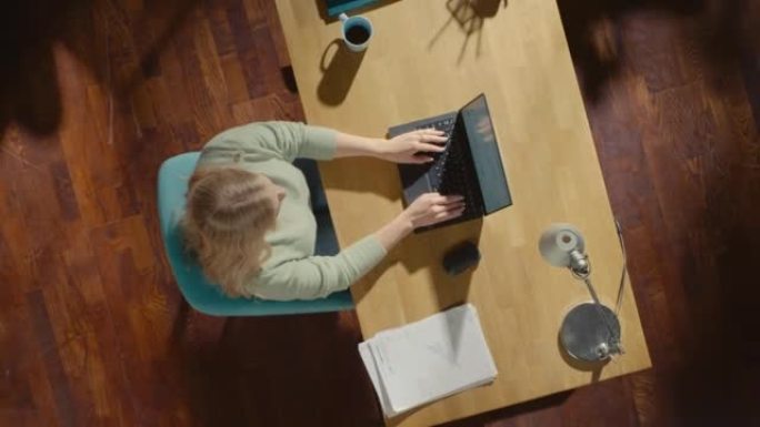 顶视图静态拍摄家庭办公室: 坐在办公桌前的自由企业家在笔记本电脑上工作。专业在家工作，远程访问公司员