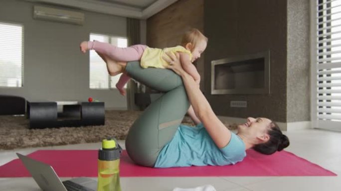 白人母亲在家在瑜伽垫上练习瑜伽时与婴儿玩耍