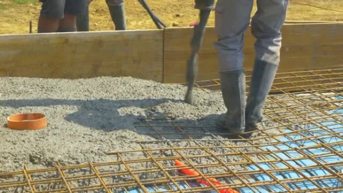 特写: 承包商将粗糙的湿混凝土倒在钢筋网上。