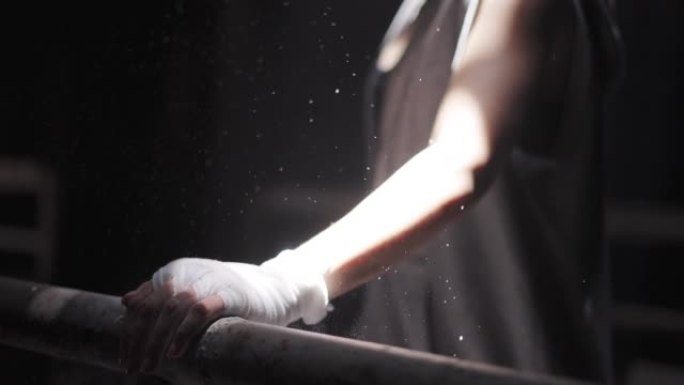 运动员用拳击绷带从手上摇动滑石粉，同时在废弃的黑暗健身房进行运动训练锻炼拳击