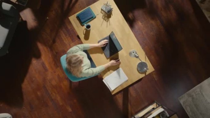 顶视图静态拍摄家庭办公室: 坐在办公桌前的自由企业家在笔记本电脑上工作。女性专业人士在家工作，远程管
