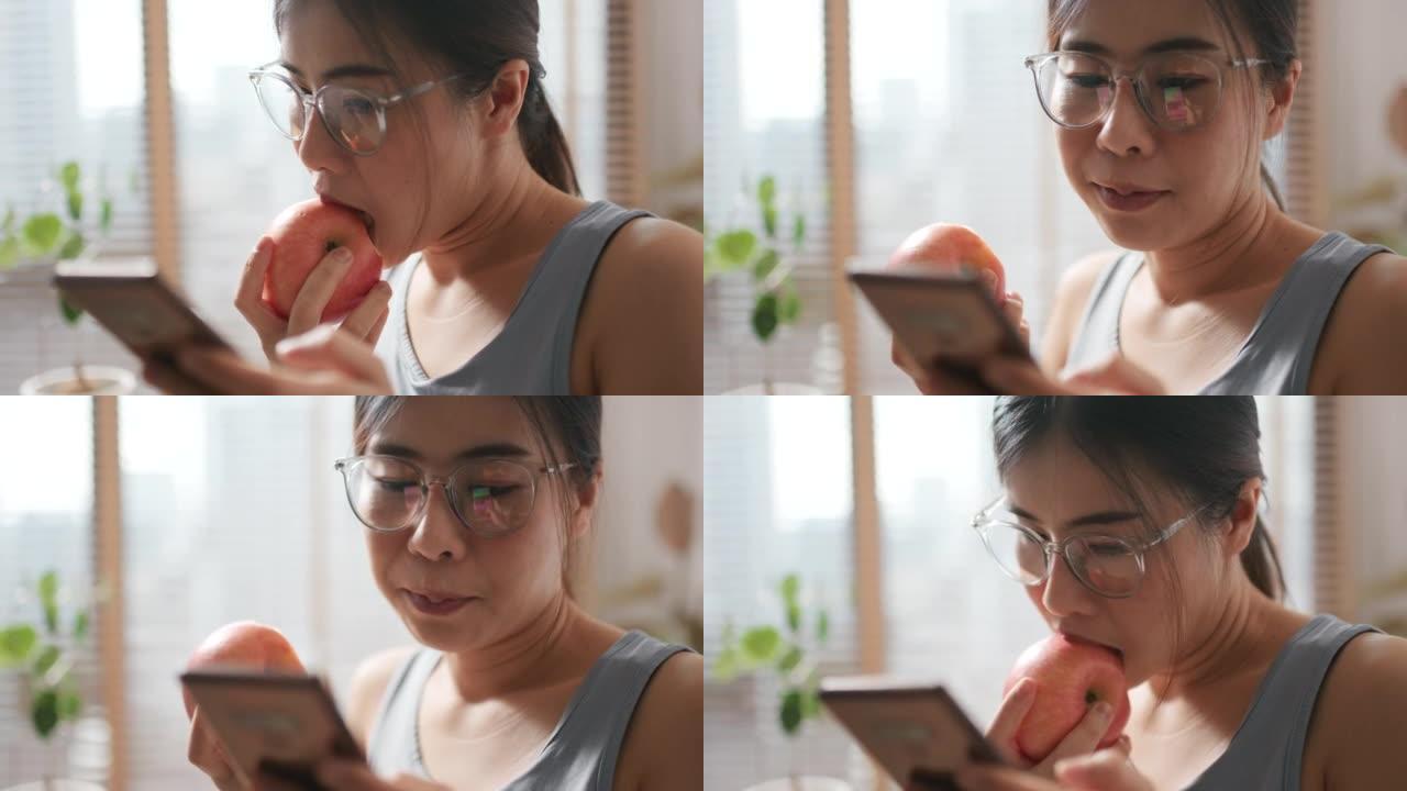 年轻女子正在吃健康的有机苹果，看着智能手机